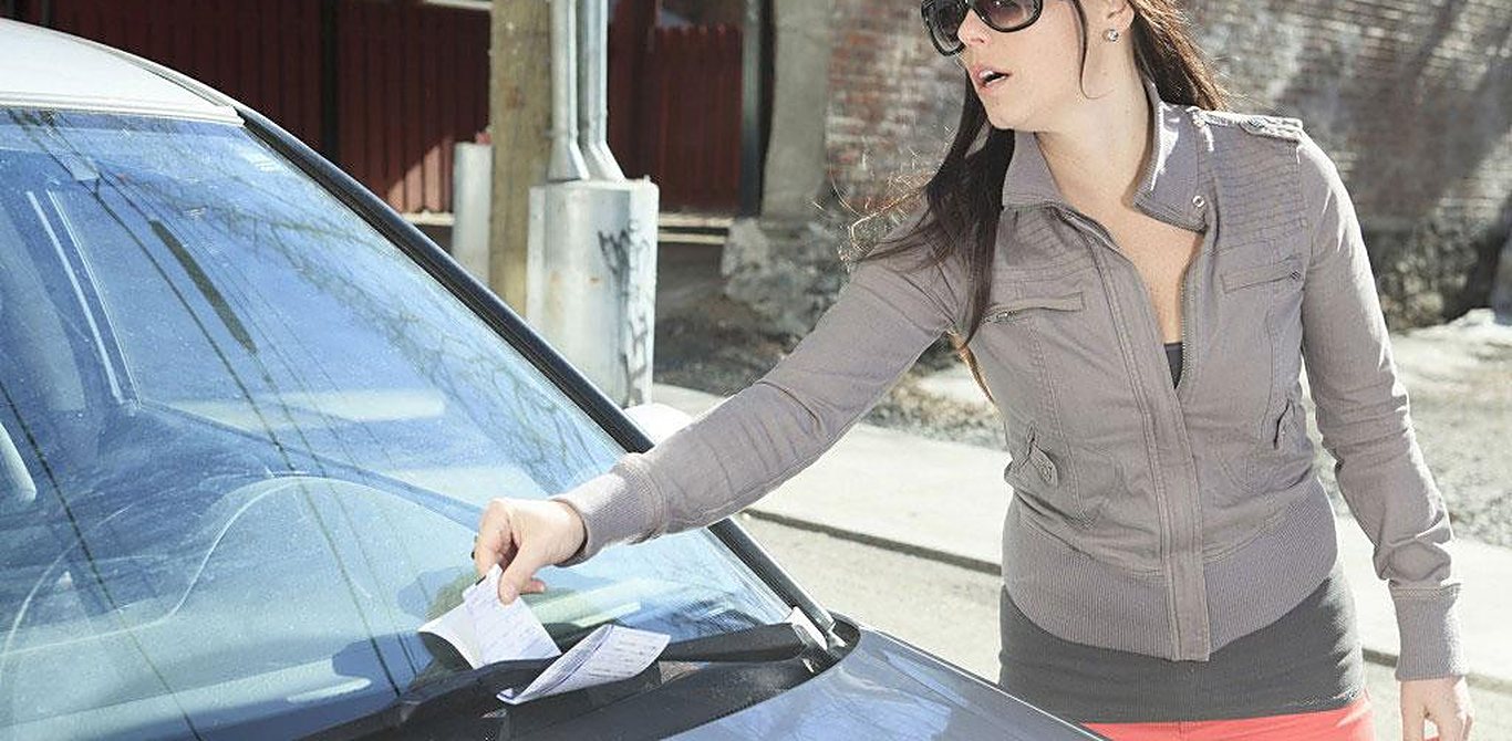 Femme retirant un constat d’infraction du pare-brise de sa voiture à Gatineau